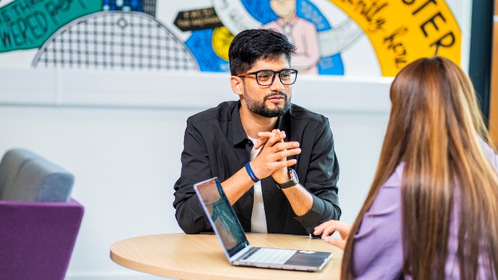 Staff member talking to a student with a laptop 